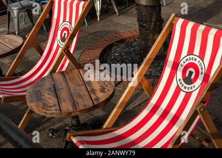 Camden town brewery logo on red and white deck chairs or deckchars and wooden table in the Anchor Pub garden on the South Bank London Stock Photo