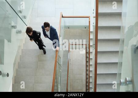 Overview of two young business people in formalwear walking upstairs Stock Photo