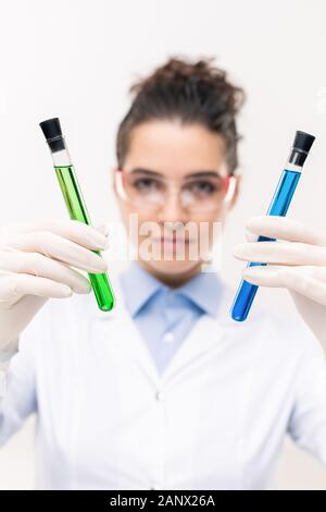 Gloved hands of female clinician or pharmacist showing flasks with vaccine Stock Photo