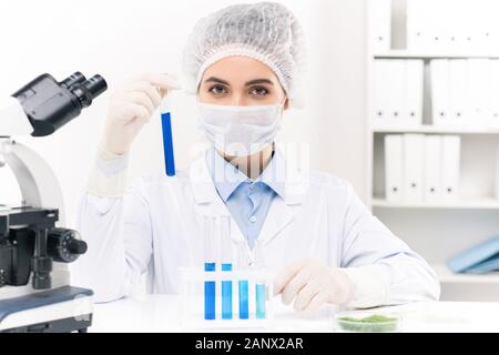 Young female laboratory worker working with liquid substances in flasks Stock Photo