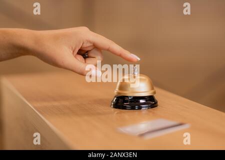 Hand of young contemporary businesswoman over call ring on reception counter Stock Photo