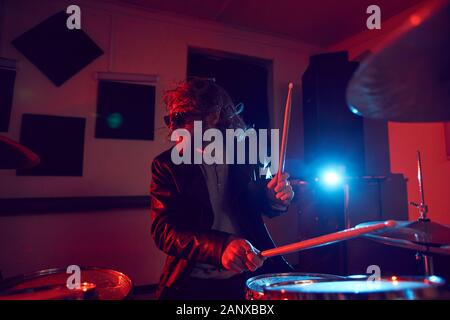 Portrait of handsome young man rocking drums during music concert in bright lights, copy space Stock Photo