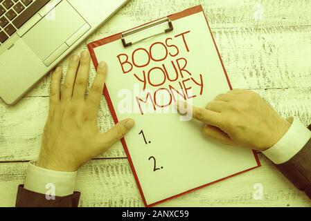Text sign showing Boost Your Money. Business photo text increase your bank saving using effective methods Hand hold writing equipment tool near modern Stock Photo