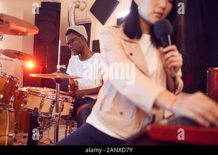 Portrait of contemporary band writing music in recording studio focus on young African man playing drums, copy space Stock Photo