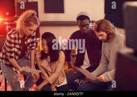 Multi-ethnic group of modern young people writing music together while rehearsing in record studio Stock Photo