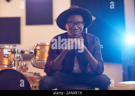 Portrait of contemporary African man looking at camera and smiling cheerfully while posing in music recording studio Stock Photo