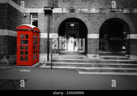 Black and white street scene with selective color on a red phone box in Sydney, Australia Stock Photo