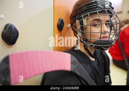 Closeup portrait of beautiful young woman wearing hockey gear and looking at camera while posing in locker room, copy space Stock Photo