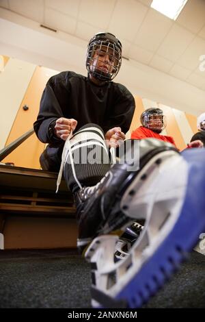 Low angle view at female hockey player putting on gear in locker room while preparing for match or practice, copy space Stock Photo