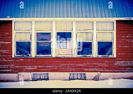 American flag hanging in the window of an old abandoned school house in the UP of Michigan Stock Photo