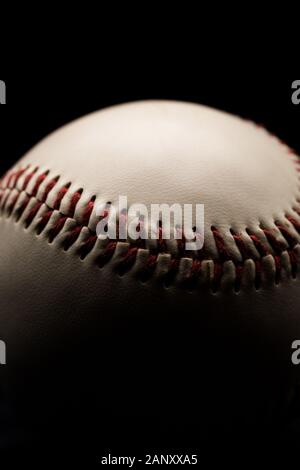 Close up of a leather baseball with red stitches. Low key, black background studio Stock Photo