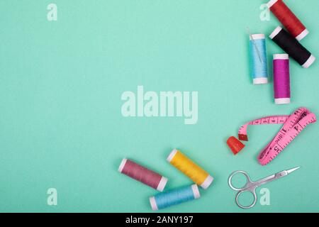 Sewing kit accessories.set tools for tailoring and colorful threads,needles,pins,scissors on mint background mockup frame top view. Stock Photo