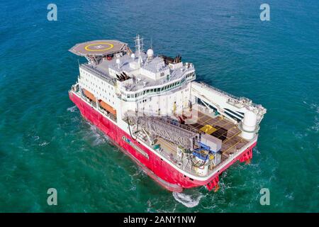 Large Platform supply ship with Helipad and two large cranes, anchored at Sea, Aerial view. Stock Photo