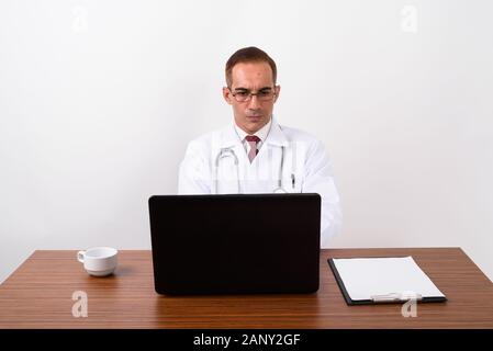 Mature Persian man doctor working behind desk Stock Photo