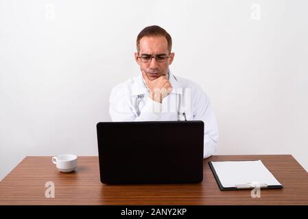 Mature Persian man doctor working behind desk Stock Photo