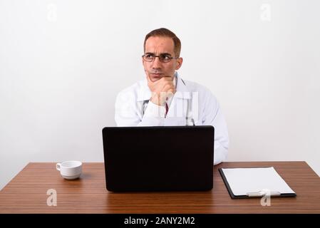 Mature Persian man doctor working behind desk Stock Photo