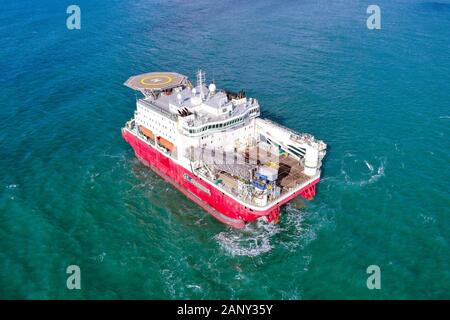 Large Platform supply ship with Helipad and two large cranes, anchored at Sea, Aerial view. Stock Photo