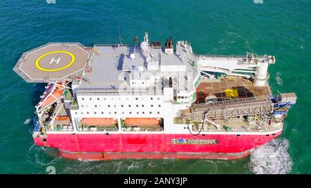 Large Platform supply ship with Helipad and two large cranes, anchored at Sea, Aerial view. Stock Photo