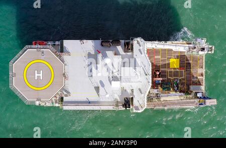 Large Platform supply ship with Helipad and two large cranes, anchored at Sea, Aerial view. Stock Photo