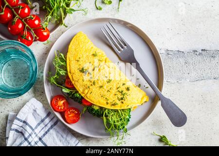 Vegan chickpea omelet with broccoli, tomatoes and seedlings on a gray plate. Healthy vegan food concept. Stock Photo