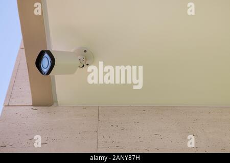 Modern CCTV camera mounted on a building wall or ceiling for outdoors surveillance, monitoring streets, homes or offices Stock Photo