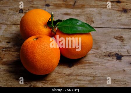 Oranges with leaves on the weathered wooden surface. Stock Photo