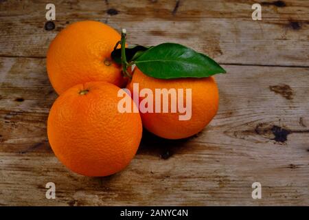 Oranges with leaves on the weathered wooden surface. Stock Photo