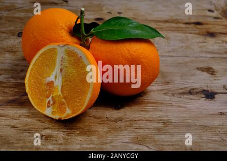 Oranges with leaves on the weathered wooden surface. Stock Photo
