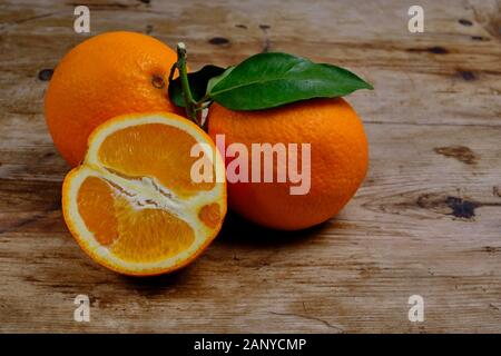 Oranges with leaves on the weathered wooden surface. Stock Photo