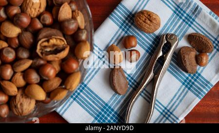 Assortment of whole nuts, walnuts, almonds, hazelnuts and Brazil nuts with nut cracker. Hard shell nuts, nutritious snack cracked and eaten in autumn Stock Photo