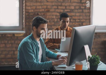 Serious good looking man typing on the keyboard Stock Photo
