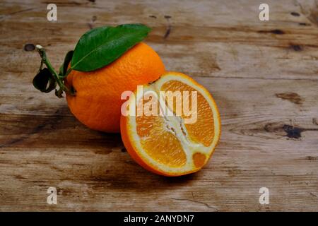 Oranges with leaves on the weathered wooden surface. Stock Photo