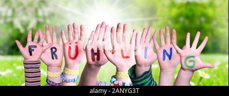 Children Hands Building Colorful German Word Fruehling Means Spring. Green Grass Meadow As Background Stock Photo