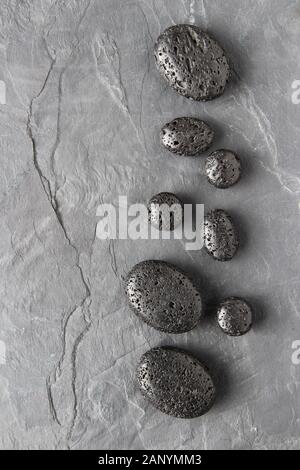 Vertical greyscale shot of lava beads on a wooden surface Stock Photo