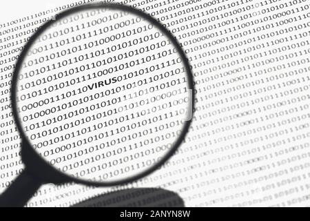 Selective focus shot through a magnifier of a white surface with virus, ones, and zeros on it Stock Photo