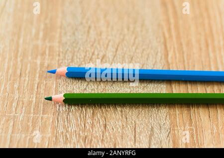 Closeup shot of two blue and green pencils on a wooden surface Stock Photo