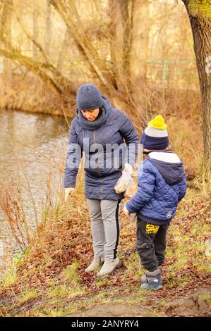 POZNAN, POLAND - Jan 12, 2020: Woman and child standing close by the water in the Debiec forest on a cold winter day. Stock Photo