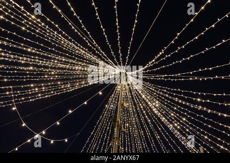 Christmas night illumination, web shape abstract, radial contrasting lines of led lights on a mast against a black sky in the city Stock Photo