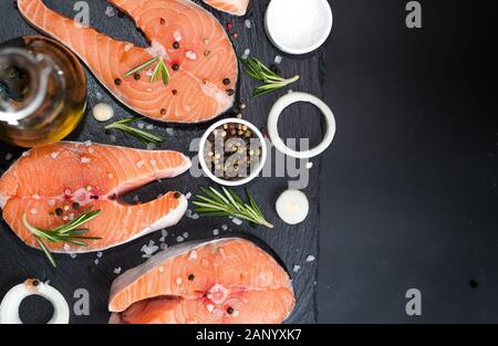 Raw salmon fish steaks with fresh herbs on cutting board Stock Photo