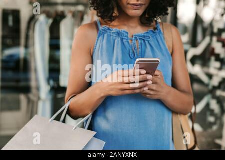 Woman using her cellphone while out shopping for clothing Stock Photo