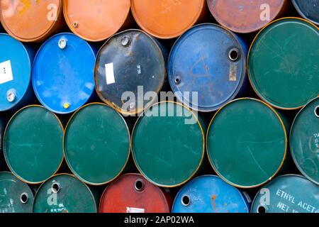Old chemical barrels. Blue, green, and red oil drum. Steel oil tank. Toxic waste warehouse. Hazard chemical barrel with warning label. Industrial Stock Photo