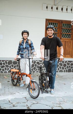 Asian young couples prepare folding bikes and wear helmets before going out Stock Photo