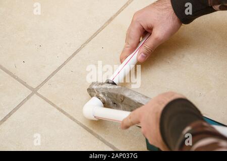 men's hands connect plastic pipes with an iron Stock Photo