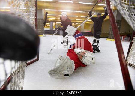 Action shot of female team playing hockey, focus on goalkeeper sliding on ice catching pluck in gate, copy space Stock Photo