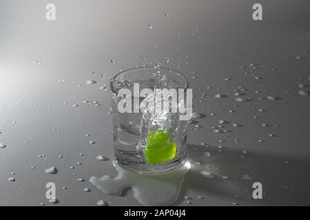 Colorful cubes dropped in a glass full of water, making beautiful splashes and wetting the table Stock Photo
