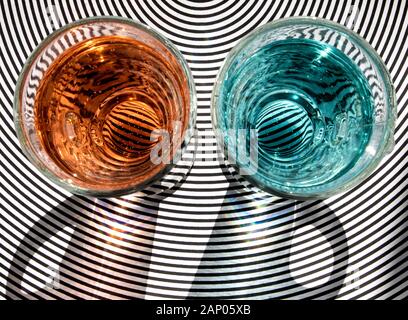 ARTISTIC ABSTRACT STILL LIFE WITH COLOURED WATER IN GLASSES AND RADIATING CIRCULAR LINES IN SUNLIGHT Stock Photo