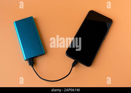 Power bank for charging mobile devices and devices. Blue smartphone charger with power bank. External battery for wireless headphones and speakers Stock Photo