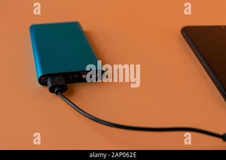 Power bank for charging mobile devices and devices. Blue smartphone charger with power bank. External battery for wireless headphones and speakers Stock Photo