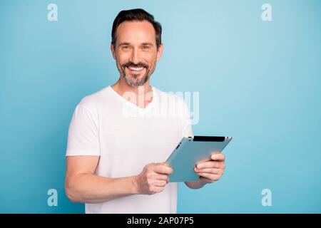 Close-up portrait of nice attractive cheerful cheery guy holding in hands digital ebook reading finance news isolated on bright vivid shine vibrant Stock Photo