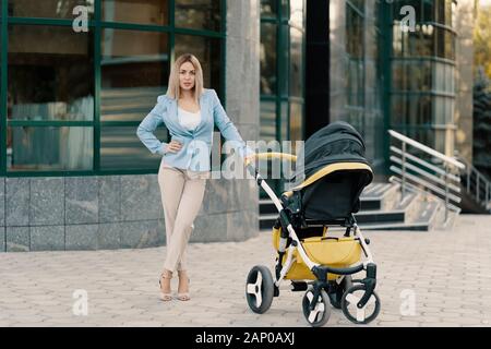 Portrait of a successful business woman in blue suit with baby near office building Stock Photo